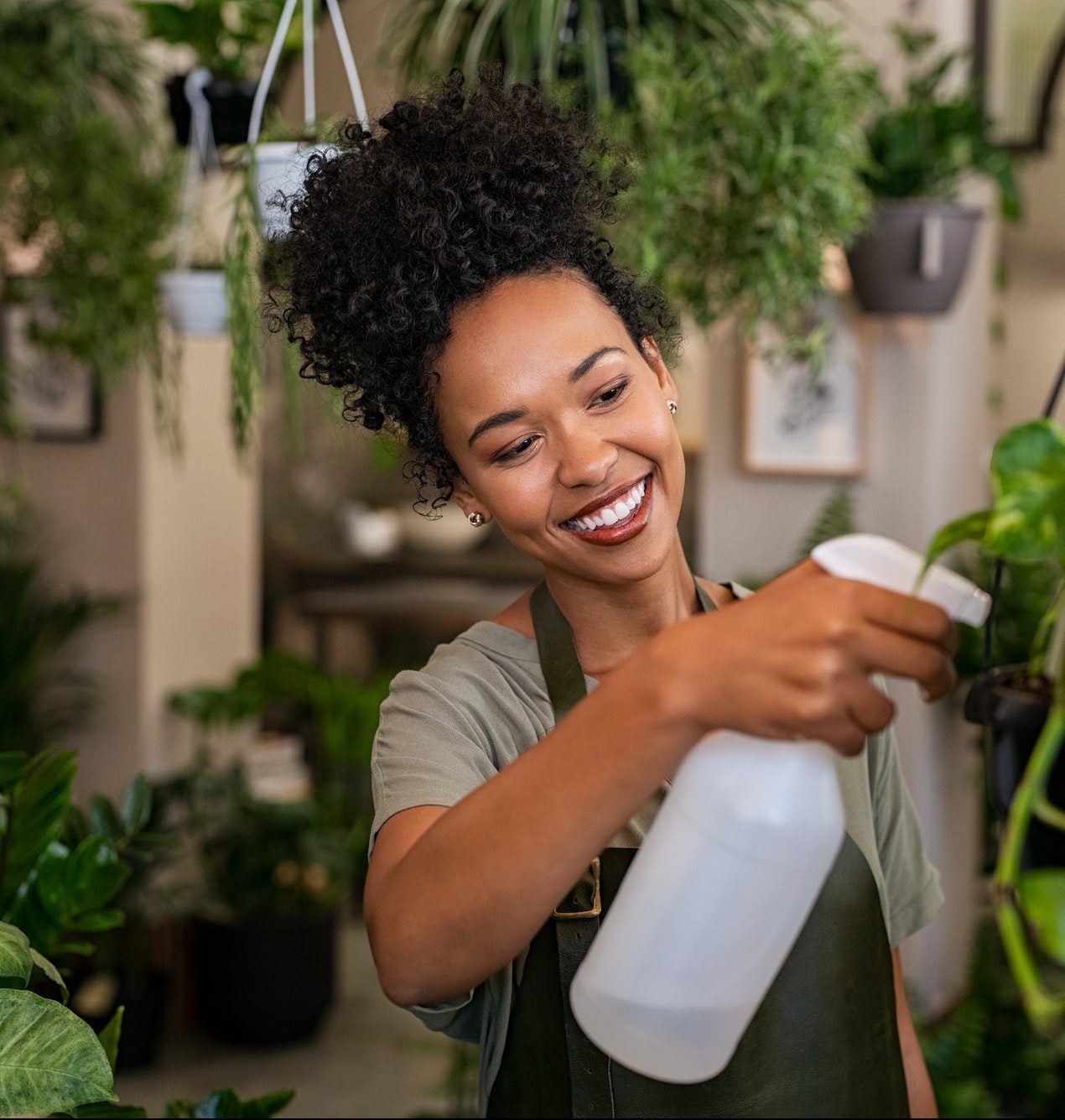 African american woman watering plants in botany shop