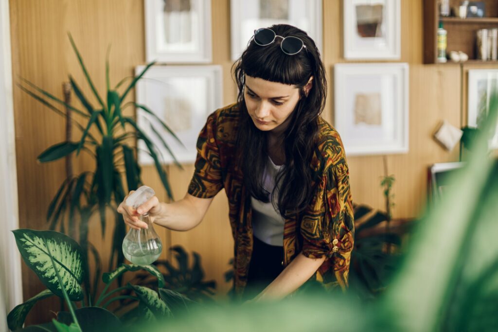 Fashionable young woman taking care of her house plants