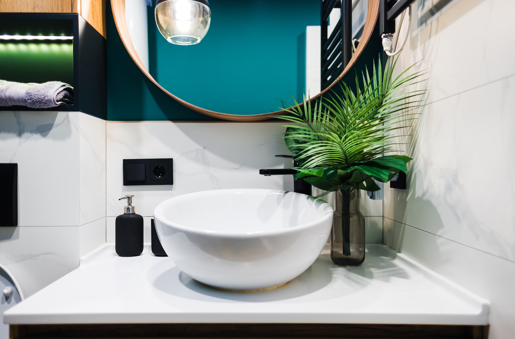 Washbasin in a modern bathroom with ornamental plants and bathroom accessories.