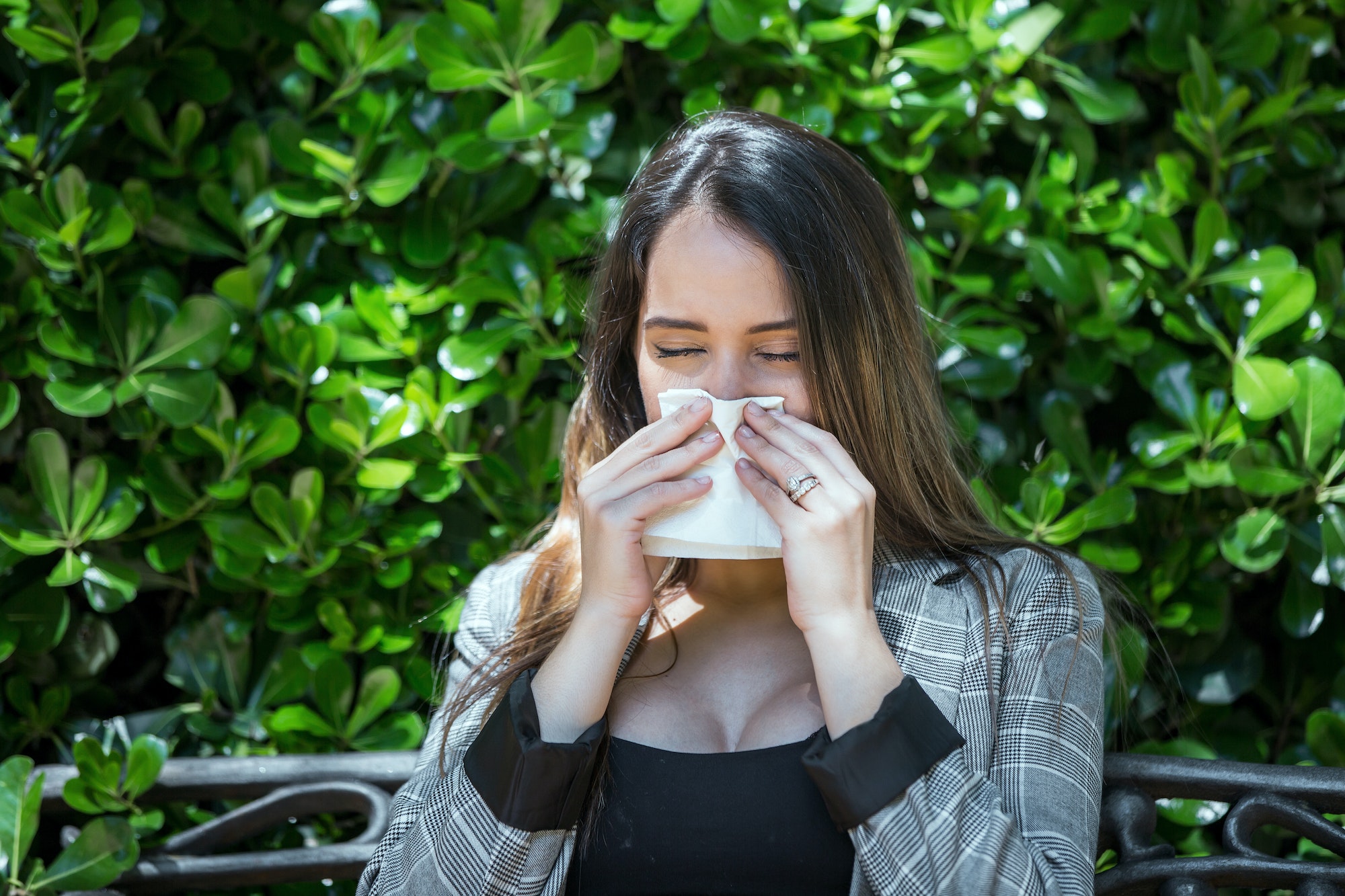 Woman with pollen allergy sneezing with closed eyes