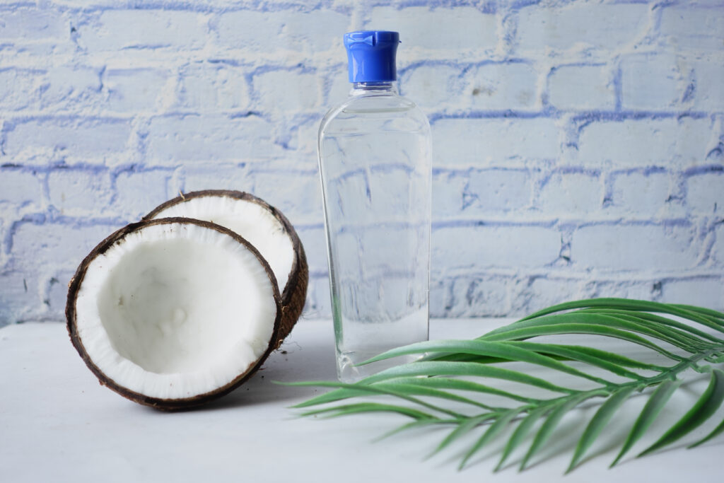 slice of fresh coconut and bottle of hair oil on a table