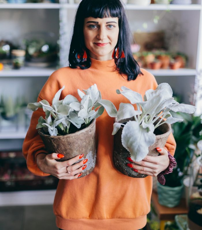 Florist holding two plants in concrete pots.