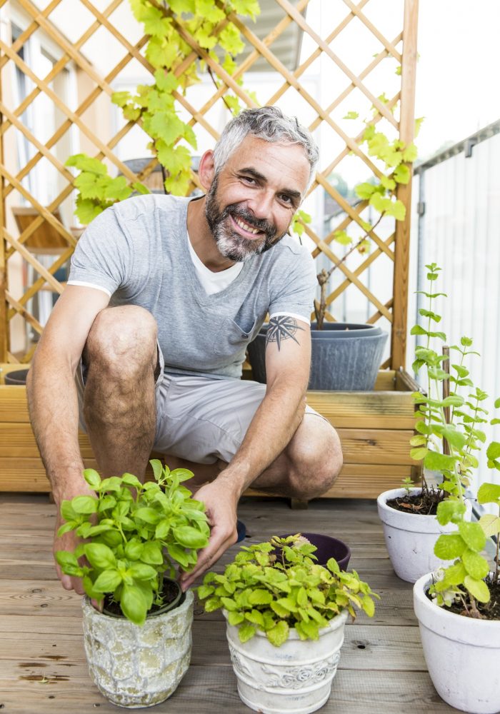 Portrait of smiling man gardening on his balcony